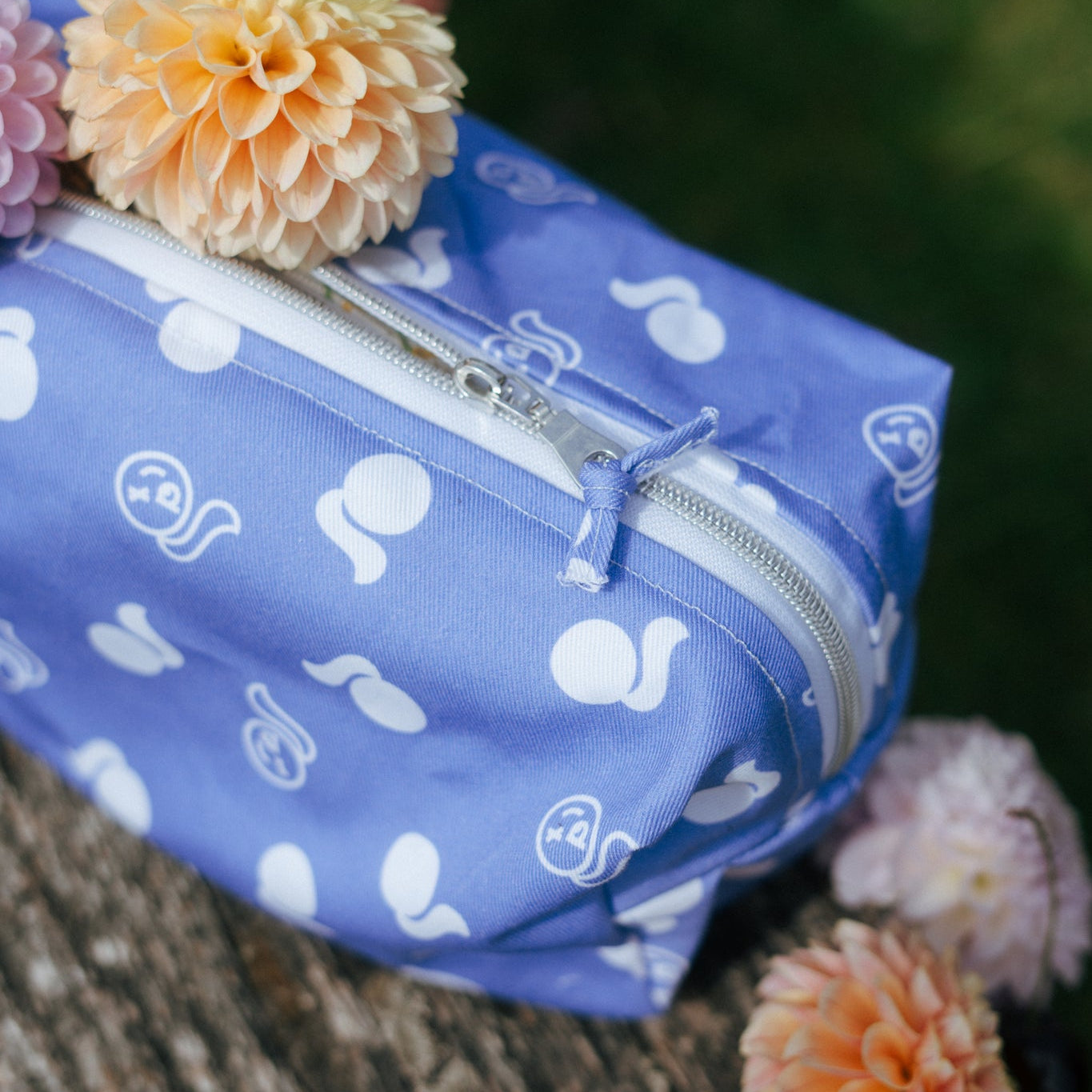 Blue bag with tough cherry logo patterns on a wooden surface with flowers