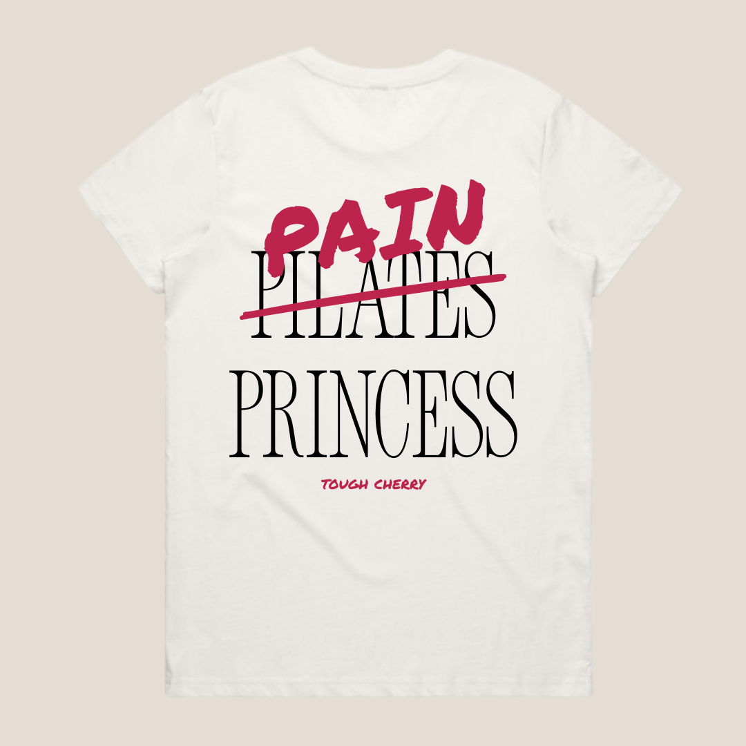 White oversized cotton t-shirt with 'Pain Princess' text in black and pink on a beige background
