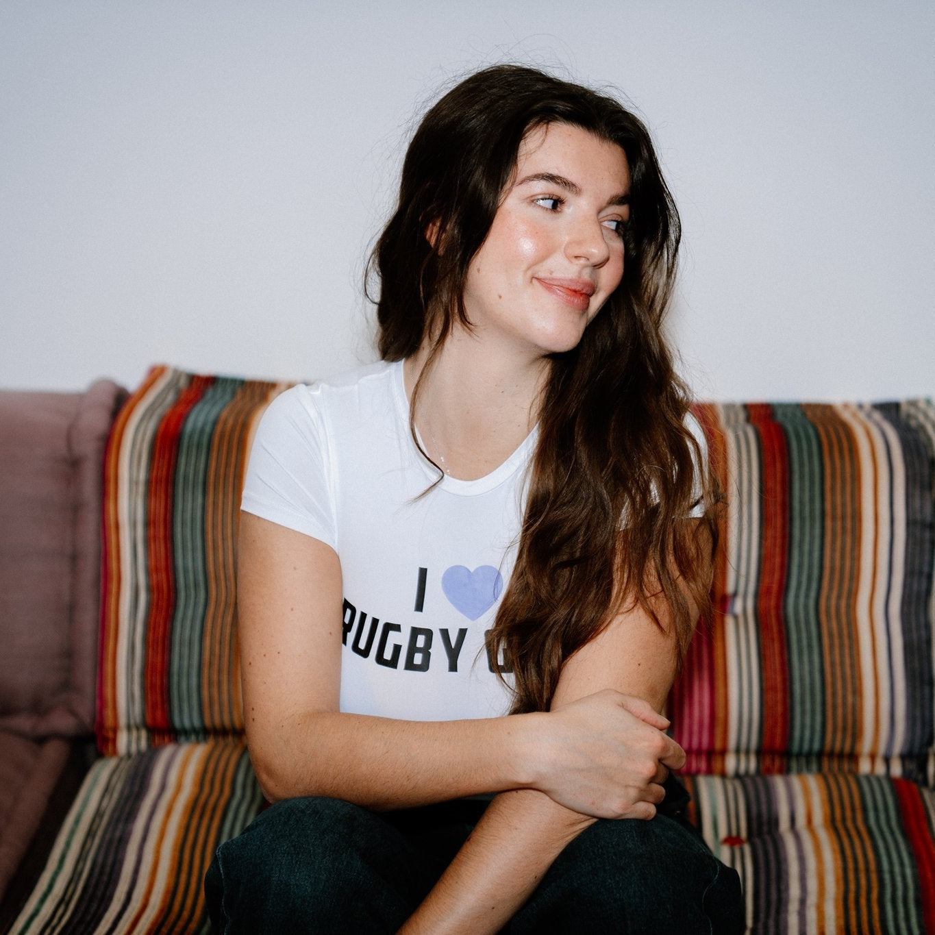 Woman sitting on a colorful couch wearing a 'I love Rugby girls' t-shirt.