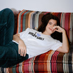 Person wearing a 'Rugby Girls' t-shirt sitting on a colorful striped couch.