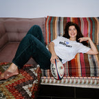 Person sitting on a colorful sofa with a rugby ball, wearing a 'Rugby Girls' t-shirt.