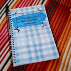 Notebook with a blue checkered cover on a striped fabric background