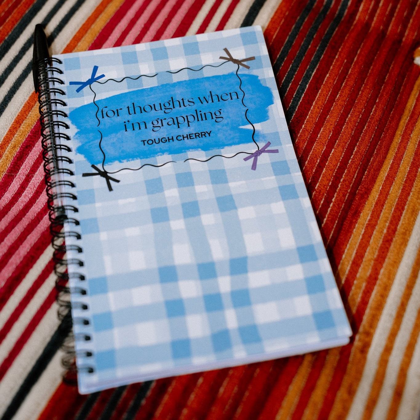 Notebook with a blue checkered cover on a striped fabric background