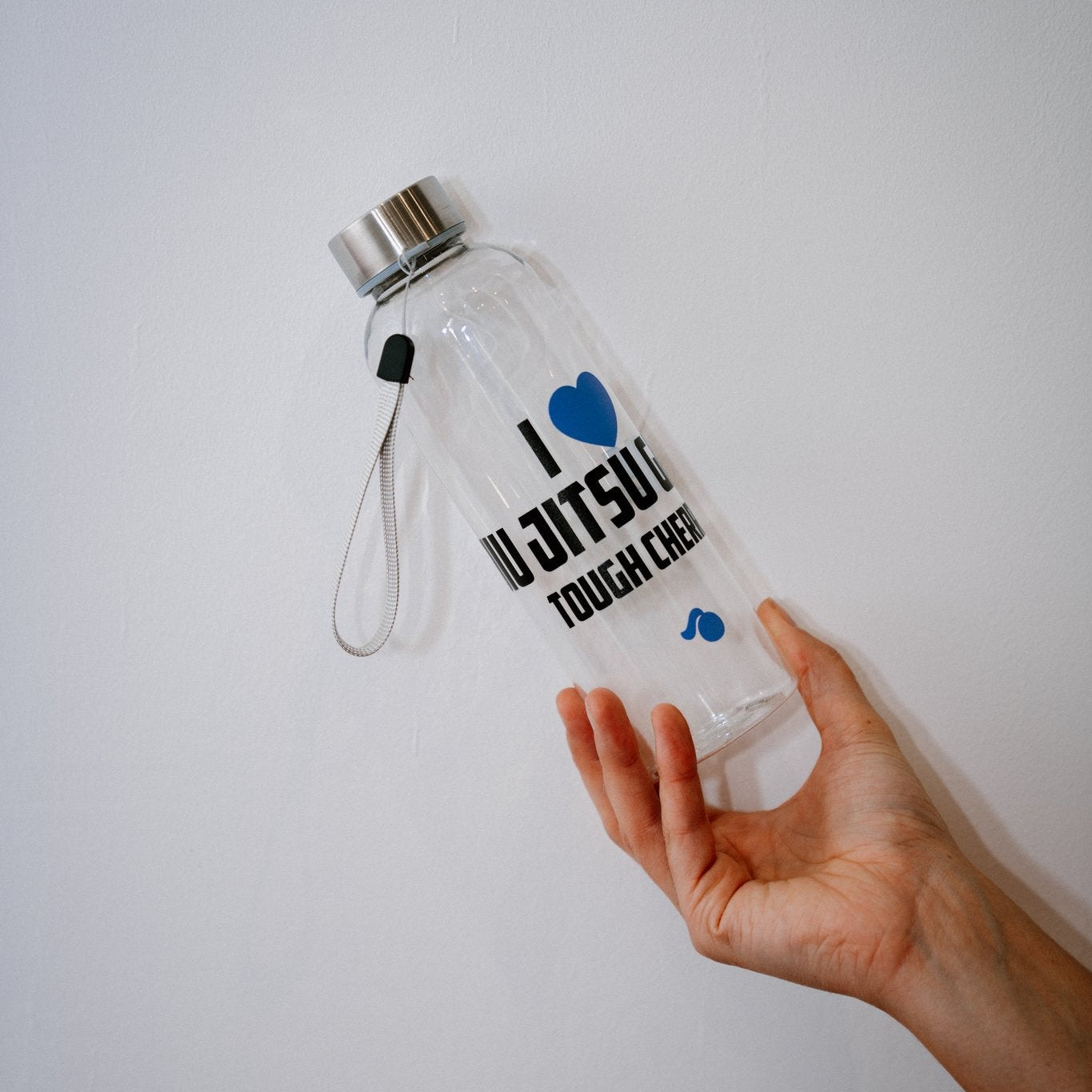 Hand holding a clear water bottle with text  'I love jiu jitsu girls tough cherry' and logos on a white background