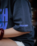 Person wearing a dark blue t-shirt with 'TOUGH CHERRY' text, blurred background