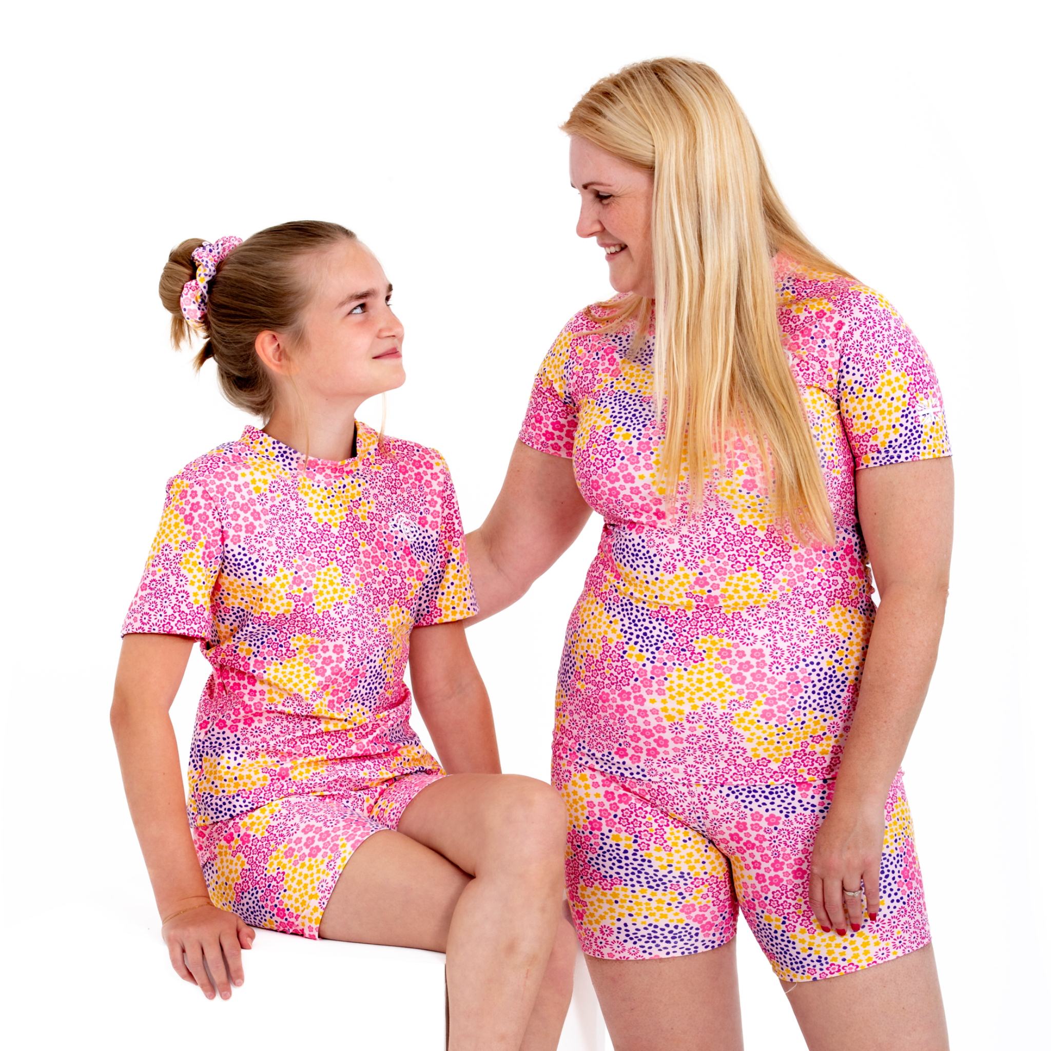 Women's and kids pink and white flower daisy design, short and long sleeved rash guard, two girls view