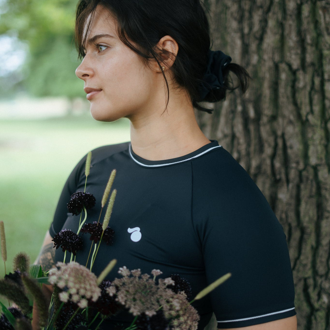 woman holding flowers wearing a black tough cherry petal rash guard in the outdors