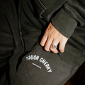 Person wearing a dark jacket with 'Tough Cherry combat lifestyle' branding on the sleeve.