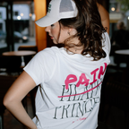 Person wearing a white t-shirt with pink and black text saying pain princess in an indoor setting