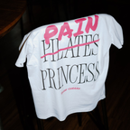 White t-shirt with pink and black text saying pain princess on a dark background