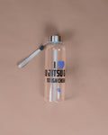 A clear plastic water bottle with a silver cap and a white straw, featuring a blue and black graphic that reads 'I [heart] JITSU TOUGH CHERRY'. The bottle is set against a solid, warm beige background.